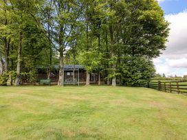 A wooden building with trees and a swing in the garden at Valley View Lodge Welshpool