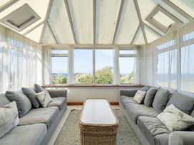 A conservatory with sofas and a table at Tregiffian Vean Sennen Cove