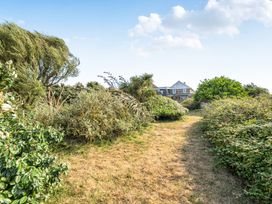 A pathway lined with bushes and trees leading to a house at Tregiffian Vean Sennen Cove