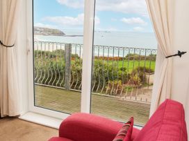 A living room with a sliding door overlooking the beach at The Lookout in Sennen