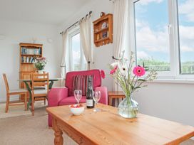 A living room with a pink sofa, coffee table and bookshelf at The Lookout in Sennen