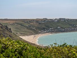 A beach with people and houses on a hillside at The Lookout in Sennen