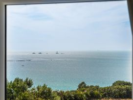 A view of the ocean from a window with a lighthouse at The Lookout in Sennen