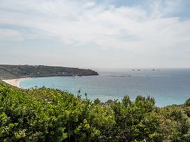A view of a beach and ocean with cliffs and houses at The Lookout in Sennen