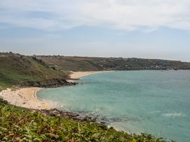 A beach with water and hills at The Lookout in Sennen