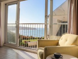A living room with an armchair and coffee cup at Brook House in Sennen Cove near St Just