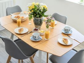 A dining room table set with croissants, juice, and flowers at Brook House Sennen Cove near St Just