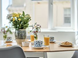A dining room table set with flowers, orange juice, croissant, and cups at Brook House in Sennen Cove near St Just
