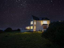 A house with illuminated windows and stars in the sky at Carn Eve Sennen Cove near St Just