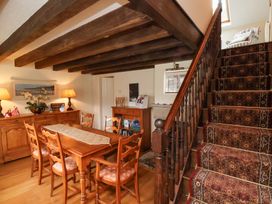 A dining room with wooden table and chairs and a staircase with carpet at Quoits Cottage in Beck Hole near Goathland