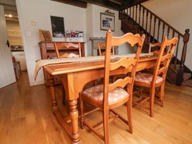 A wooden dining table with chairs in a dining room with wooden floors and a staircase at Quoits Cottage in Beck Hole near Goathland