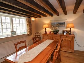 A dining room with a wooden table and chairs a sideboard with lamps curtains and beams on the ceiling at Quoits Cottage in Beck Hole near Goathland