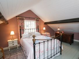 A bedroom with a metal bed frame two bedside tables lamps and a wooden chest at Quoits Cottage in Beck Hole near Goathland