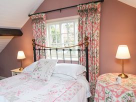 A bedroom with a bed a floral quilt floral curtains two lamps and a round table at Quoits Cottage in Beck Hole near Goathland