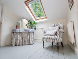 A room with striped armchair and a vanity table with mirror under a skylight window at Quoits Cottage Beck Hole near Goathland