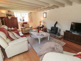 A living room with a sofa, armchair, coffee table and television at Quoits Cottage in Beck Hole near Goathland