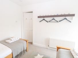 A bedroom with twin beds and a shelf with hangers at Driftwood Cottage in Heacham