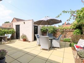 A garden with a patio set and shed at Driftwood Cottage in Heacham