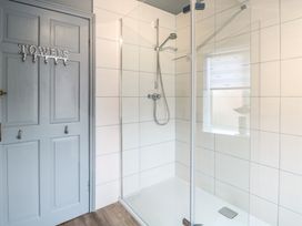 A shower with glass doors and grey door at Driftwood Cottage Heacham