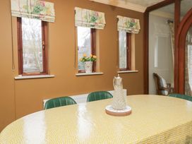 A dining room with a round table and windows at Kempton in Bowness-on-Windermere