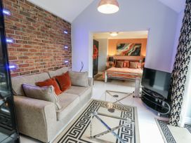A living room with a sofa, coffee table, and bed at Smithy Cottage in Cemaes Bay