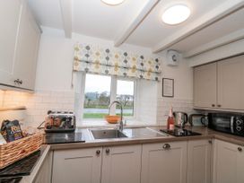 A kitchen with various appliances and a window at Wold Cottage in Hunmanby
