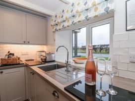 A kitchen with a sink and bottle of champagne at Wold Cottage in Hunmanby