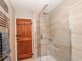 A shower area with a glass door and wooden door at Wold Cottage in Hunmanby