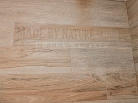 A close-up of wooden-style flooring with text at Wold Cottage in Hunmanby