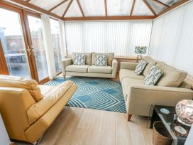 A conservatory with sofas and a coffee table at 1 The Old Smithy Cemaes Bay