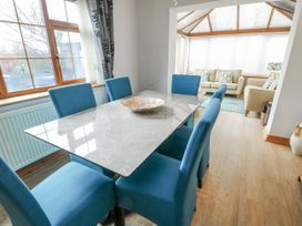 A dining room with a table and chairs leading to a conservatory at 1 The Old Smithy in Cemaes Bay