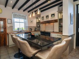 A kitchen with a granite island and bar stools at The Farmhouse in Boggle Hole near Robin Hood's Bay