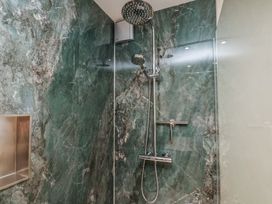 A shower with marble walls and a shower head at The Farmhouse in Boggle Hole near Robin Hood's Bay