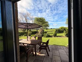A garden with a table and chairs under an umbrella at The Farmhouse in Boggle Hole near Robin Hood's Bay
