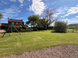 A garden with a swing set and trees at The Farmhouse in Boggle Hole near Robin Hood's Bay