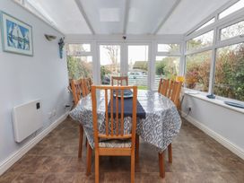 A conservatory with a dining table and chairs at Dolfor in Nefyn
