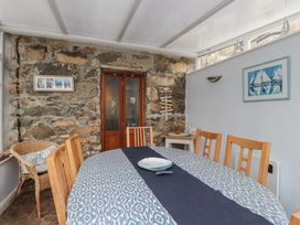 A dining room with a stone wall and wooden furniture at Dolfor in Nefyn