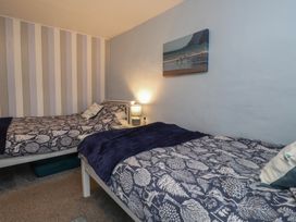 A bedroom with two beds and a lamp at Dolfor Nefyn