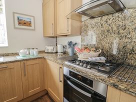 A kitchen with cabinets, stove, oven, sink, and utensils at Roma in Rhos-on-Sea