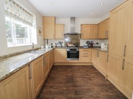 A kitchen with wooden cabinets and granite countertops at Roma in Rhos-on-Sea