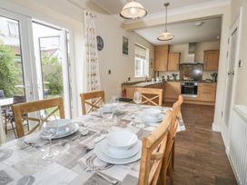 A dining room with a table set for meals and a kitchen in Roma Rhos-on-Sea