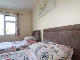 A bedroom with two beds and a window at Merlin's Retreat in Tintagel