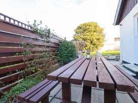A garden with a wooden table and glasses at Merlin's Retreat in Tintagel