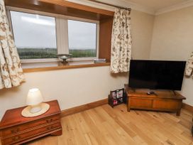 A living room with a television and lamp at Long Cart Cottage in Embleton