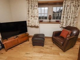 A living room with a television and armchair at Long Cart Cottage in Embleton
