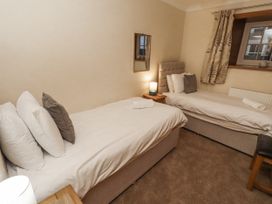 A bedroom with two beds and a mirror at Long Cart Cottage in Embleton