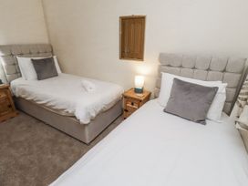 A bedroom with two single beds and a nightstand at Long Cart Cottage in Embleton