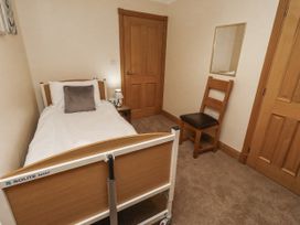 A bedroom with a bed and chair at Long Cart Cottage in Embleton