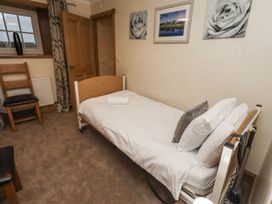 A bedroom with a single bed and a chair at Long Cart Cottage in Embleton