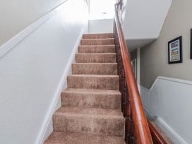 A staircase with carpeted steps and a wooden handrail at The View in Criccieth